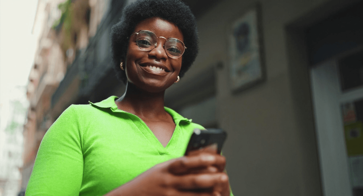 Colaboradora motivada sorrindo e usando o celular